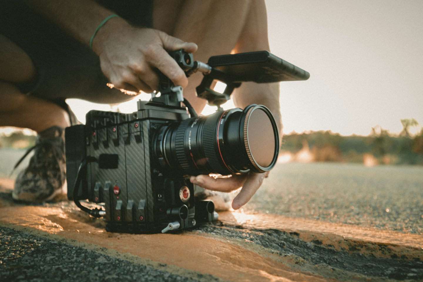 Filmmaker knielt op straat en bedient een professionele filmcamera.